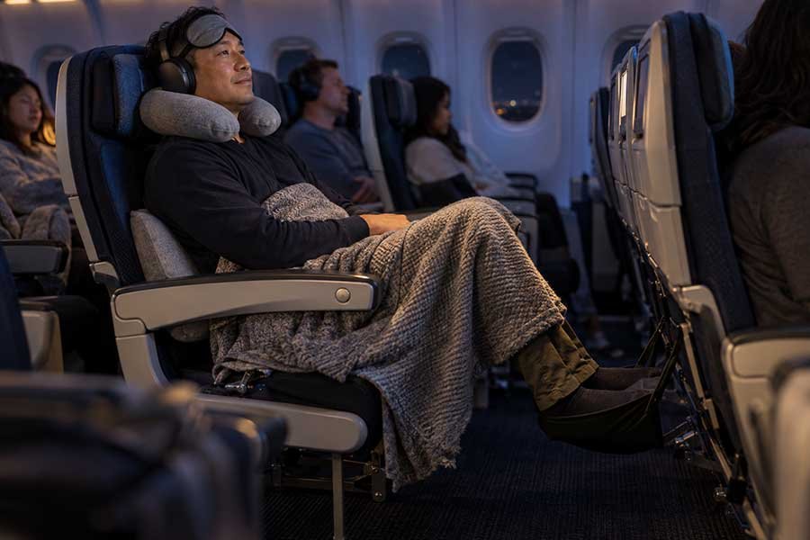 A traveler resting comfortably with an eye mask and blanket on a long flight
