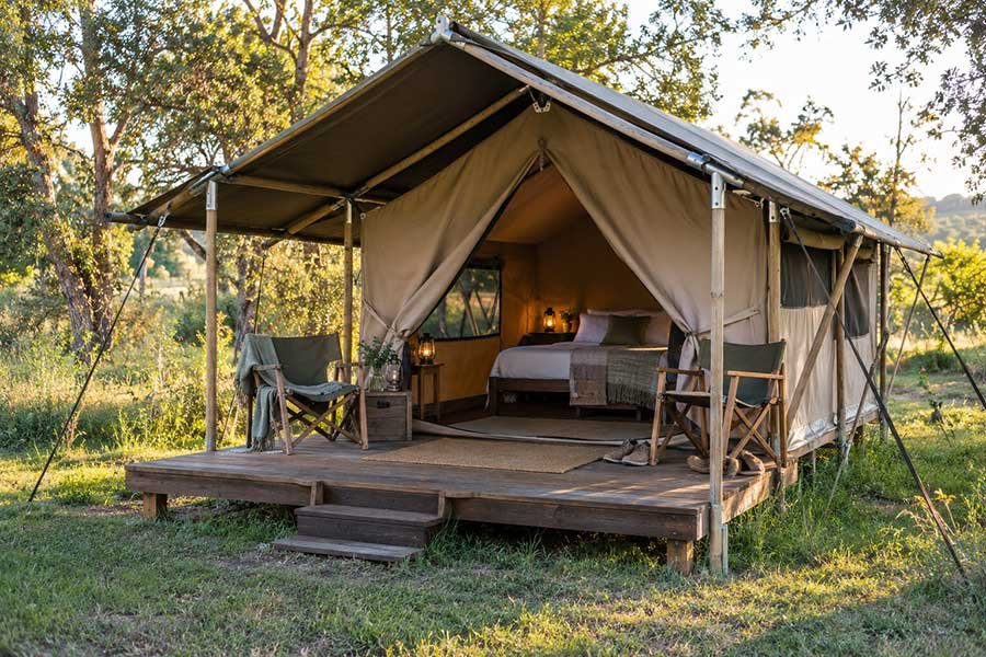 Cozy glamping tent with warm lights glowing at dusk among trees on a simple first getaway