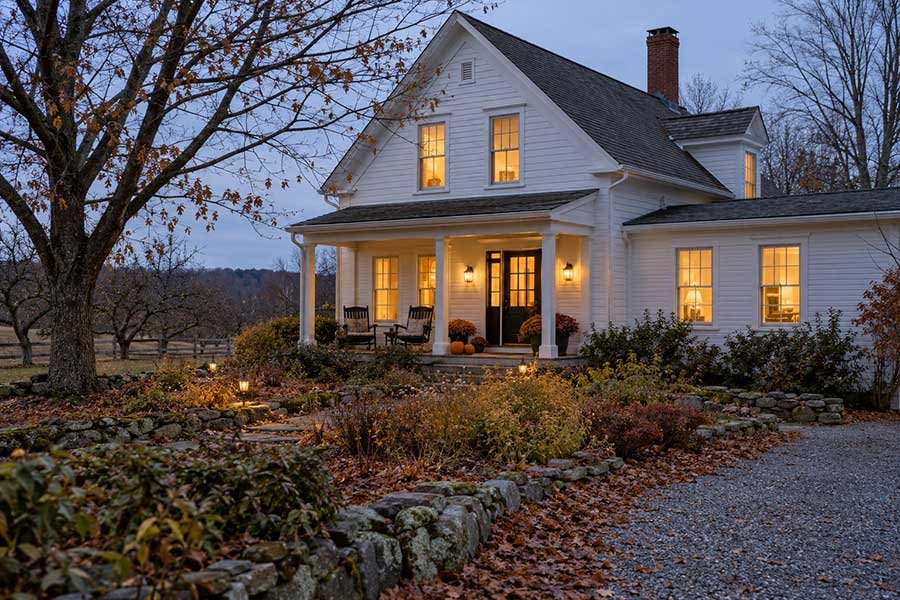 Cozy farmhouse retreat glowing at blue hour on an autumn evening, ideal for a short Thanksgiving trip