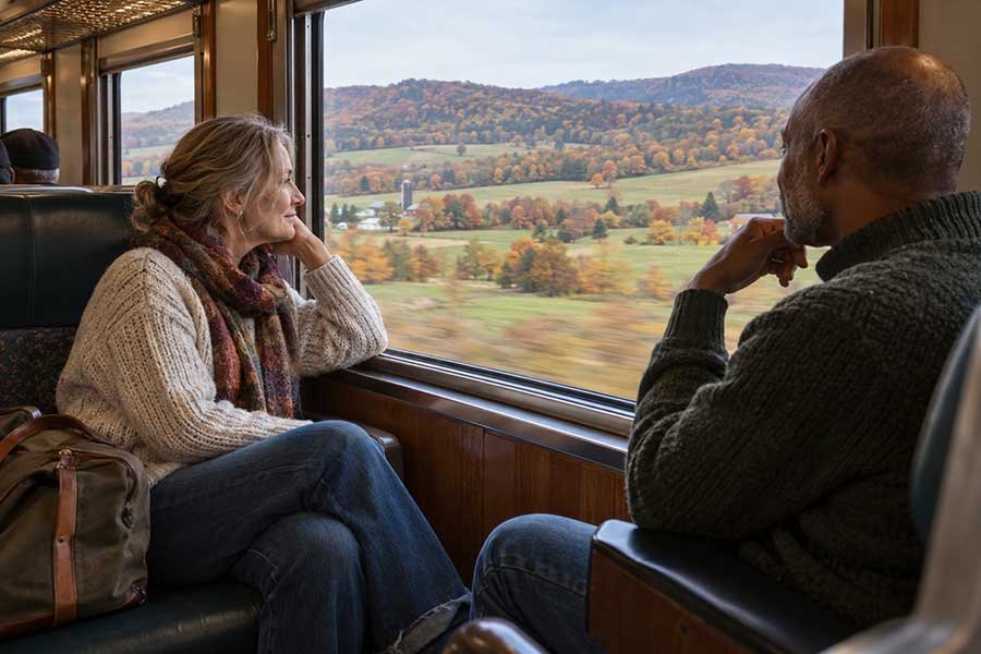 Couple on a scenic autumn countryside train ride, watching golden fields pass by the window