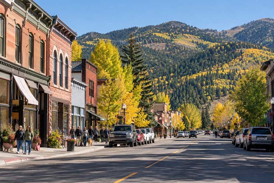 Autumn main street in a Rocky Mountain town with golden trees and mountains behind the shops