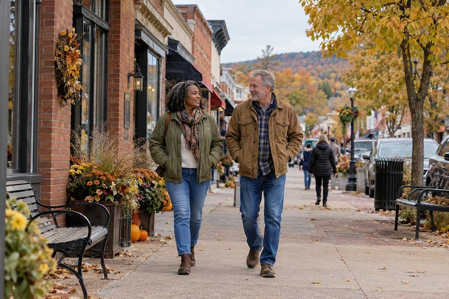Travelers strolling along a quiet village street lined with autumn trees on a scenic drive