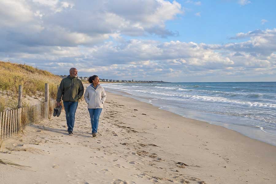 Couple strolling along a quiet Atlantic beach in autumn under a soft, cloudy sky