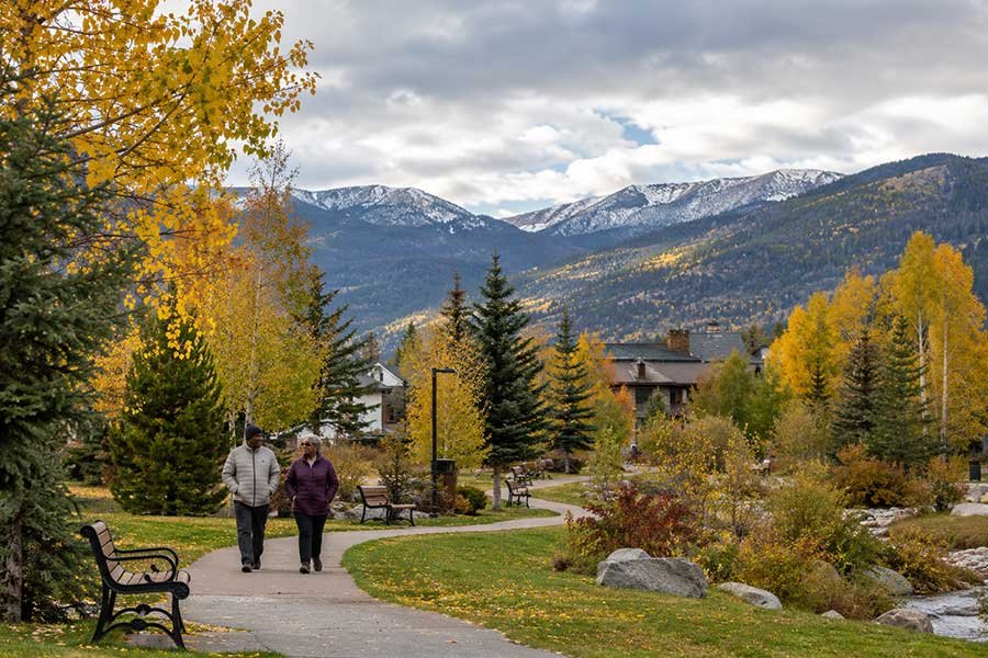 Couple walking along a mountain town street in autumn past shops and golden trees