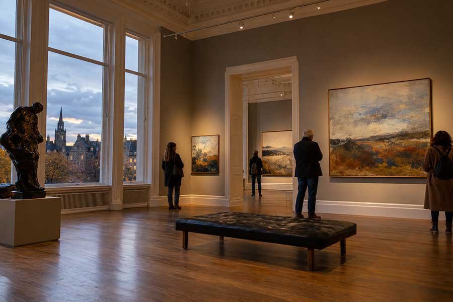 Visitors arriving at a city museum at autumn dusk with warm lights glowing in the windows