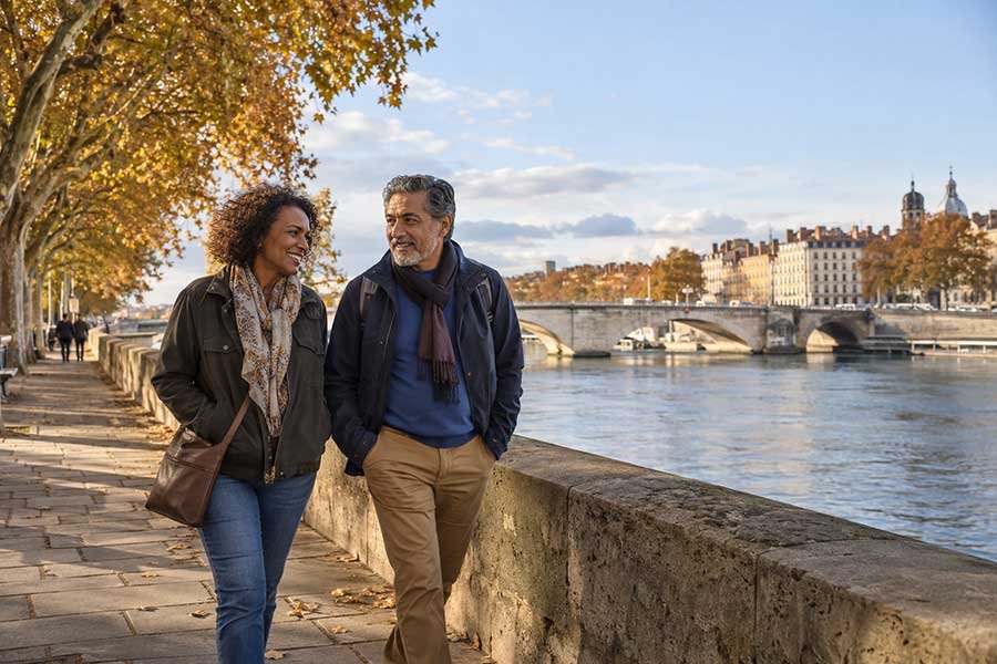 Couple strolling along a city river path in autumn with colorful trees and city buildings