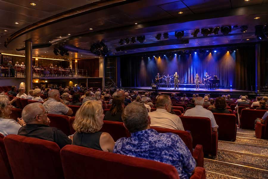 Cruise ship theater with empty red seats just before showtime and warm stage lighting