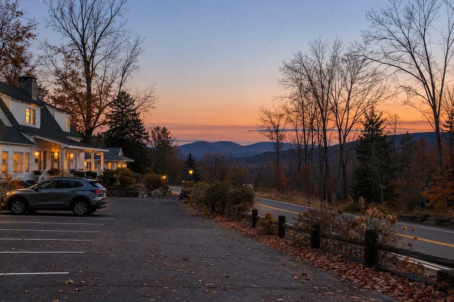 Rural inn glowing in early dusk light with a quiet country road in autumn