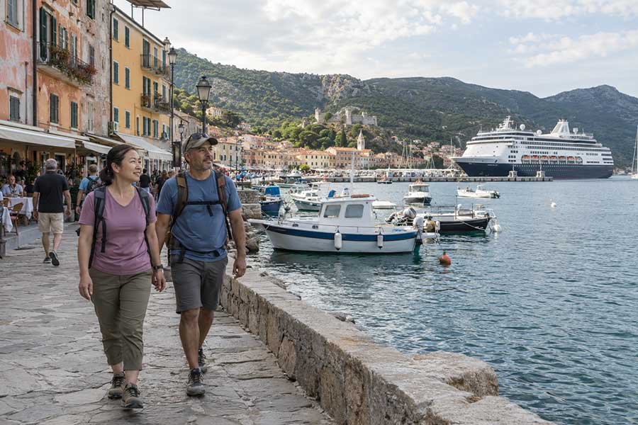 Travelers exploring a sunny Mediterranean harbor after arriving by cruise ship