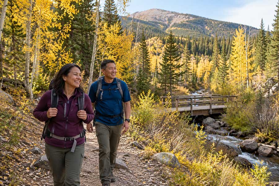 Hiker walking a mountain trail lined with golden aspen trees in autumn