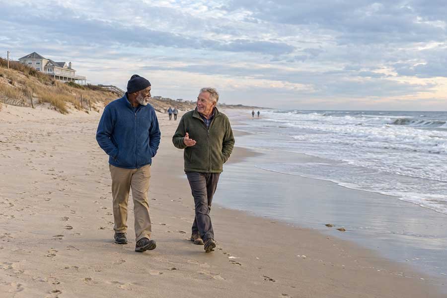 Friends walking along a warm beach in late November during a Thanksgiving getaway