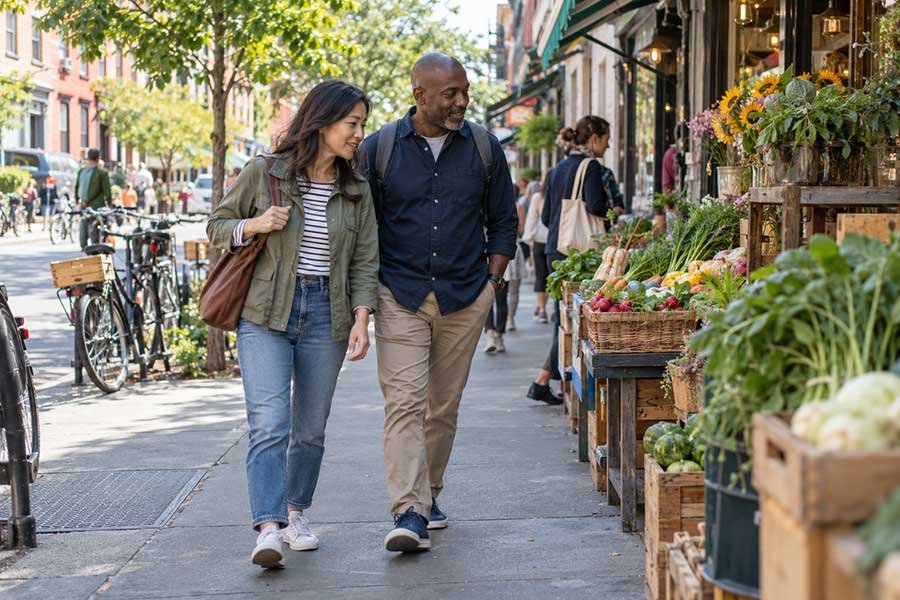 Couple strolling through a lively weekend market with colorful stalls and fresh produce