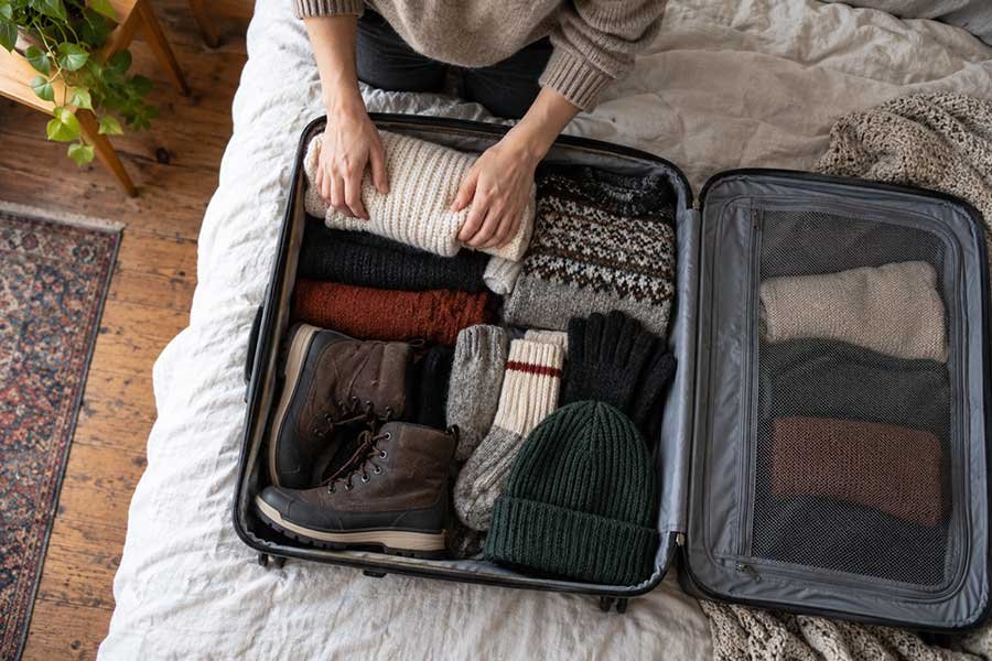 Open suitcase packed with warm layers for a winter getaway