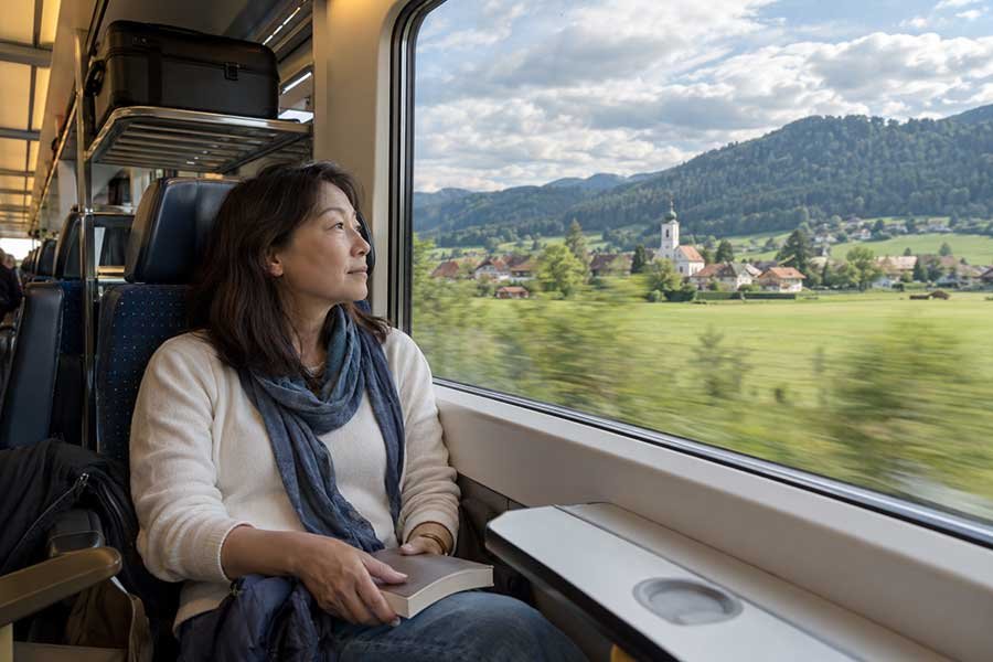 Traveler on a quiet train journey through the European countryside past green fields and villages