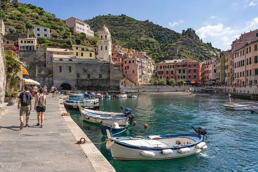 Travelers strolling along a colorful Ligurian harbor in Italy on a first Europe trip