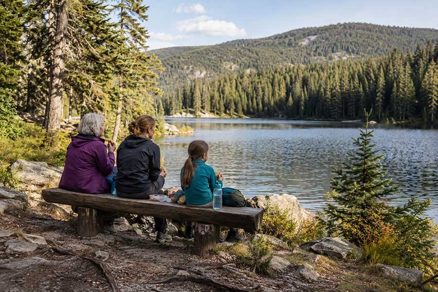Three generations of a family sitting together by a lake, sharing a quiet moment