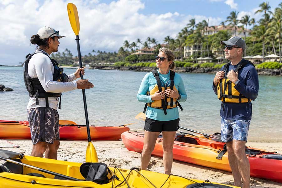 Guests receiving a kayaking briefing on a tropical resort beach before heading out on the water