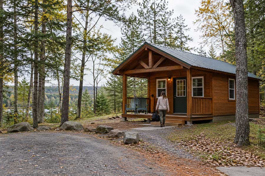 Small campground cabin with a porch, surrounded by trees, ready for a first stay